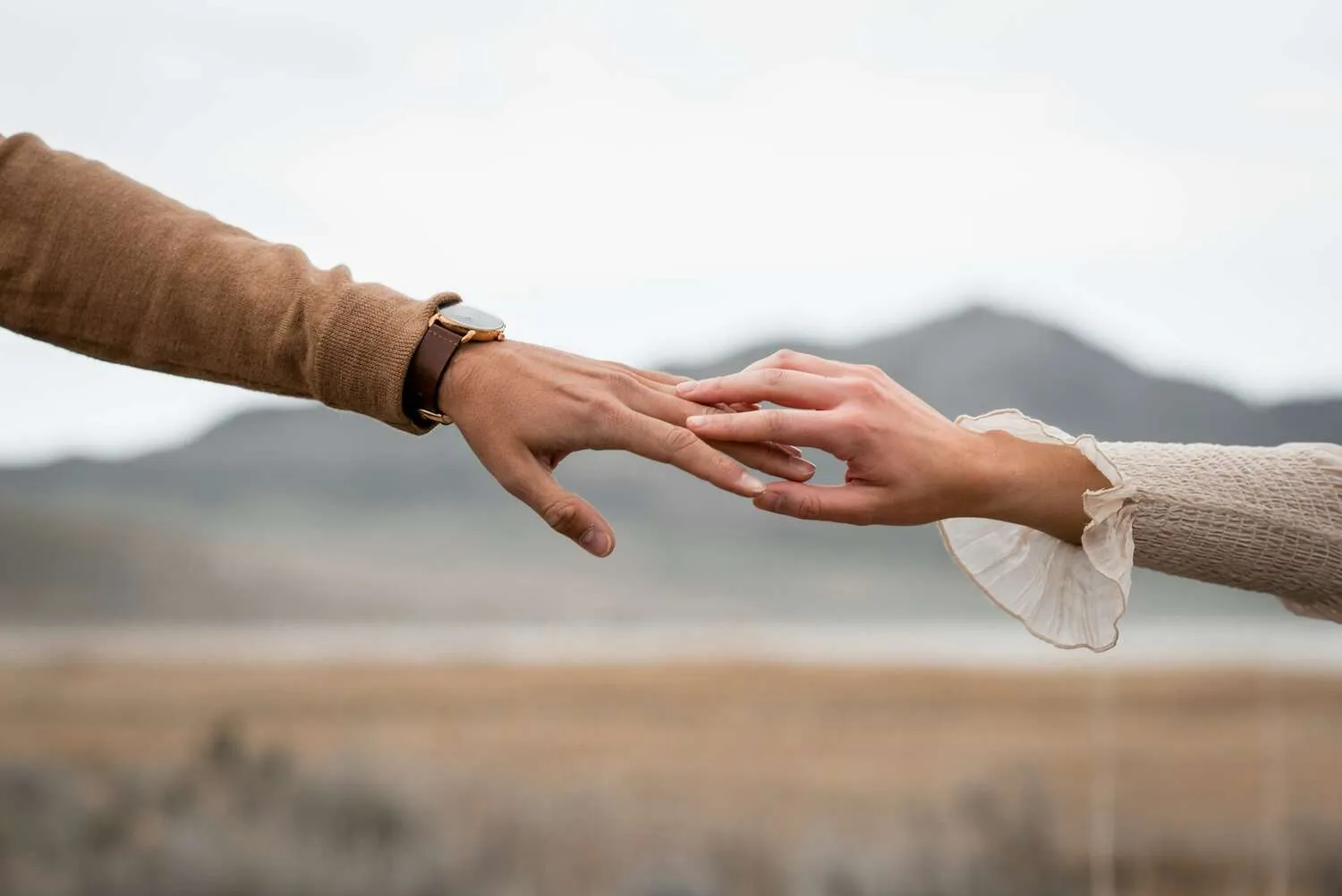 Two partners reaching toward each other, hands almost touching